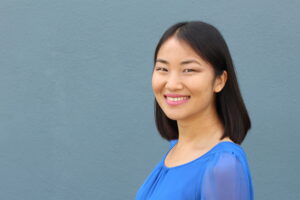 Woman in blue top smiling on blue background